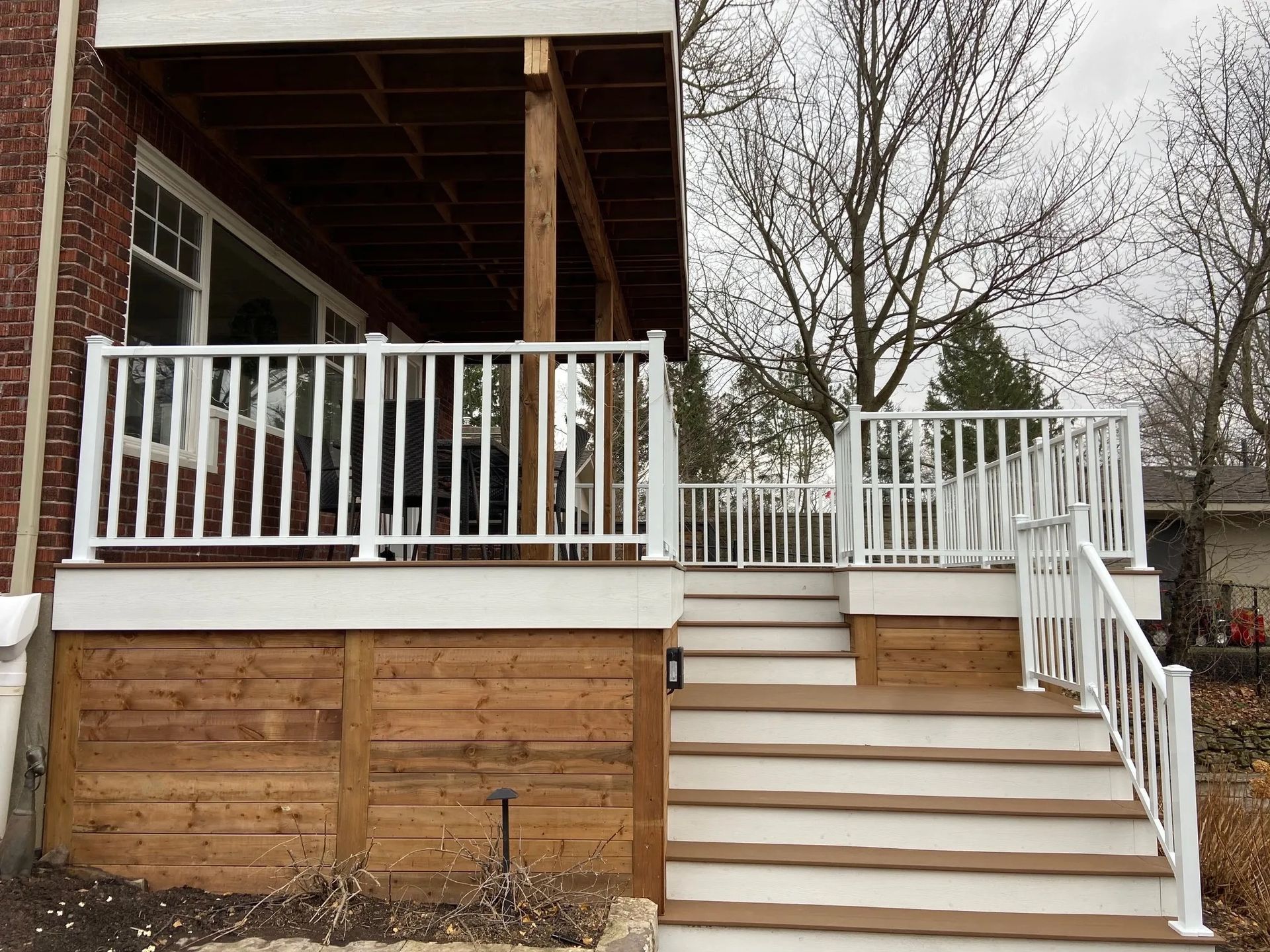A deck with stairs leading up to it and a white railing.