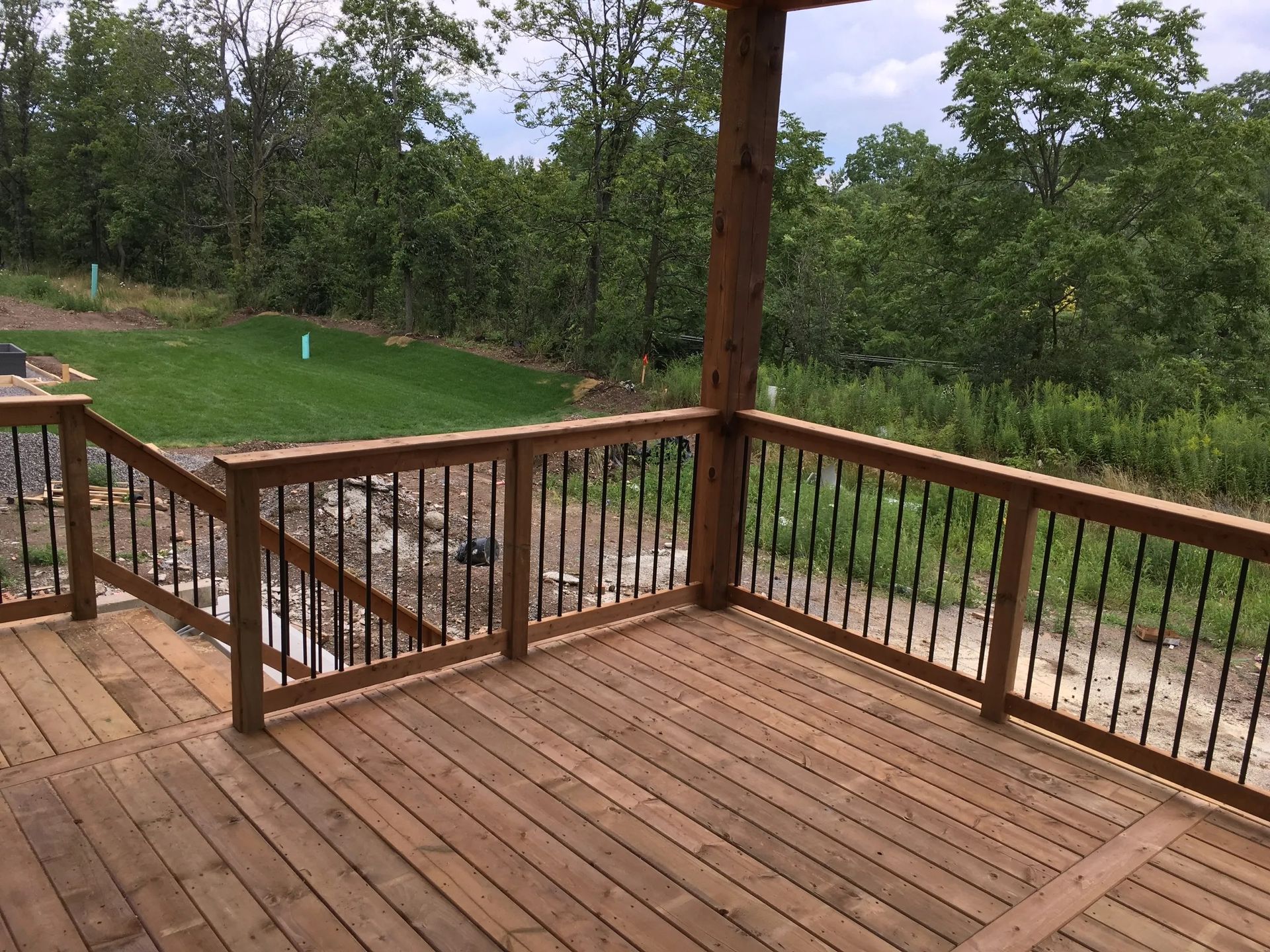 A wooden deck with a metal railing and stairs leading up to it.