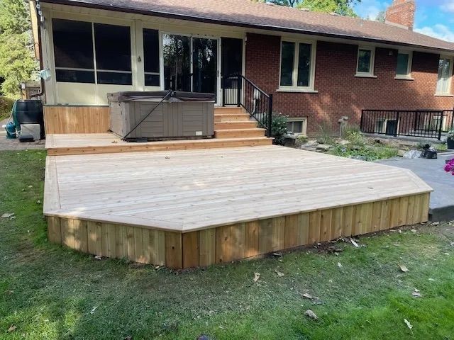 A wooden deck with a hot tub in the backyard of a house.