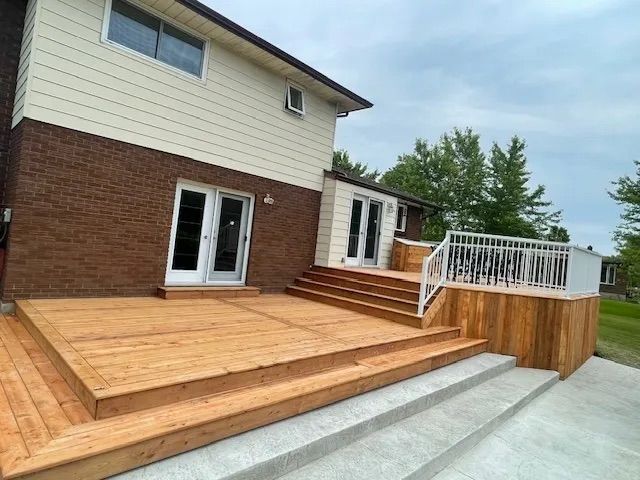 The back of a house with a wooden deck and stairs.