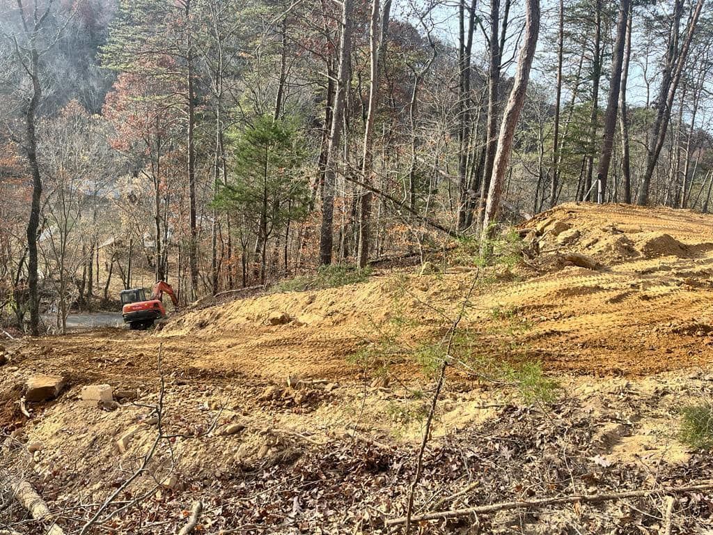 A bulldozer is moving dirt in the middle of a forest.