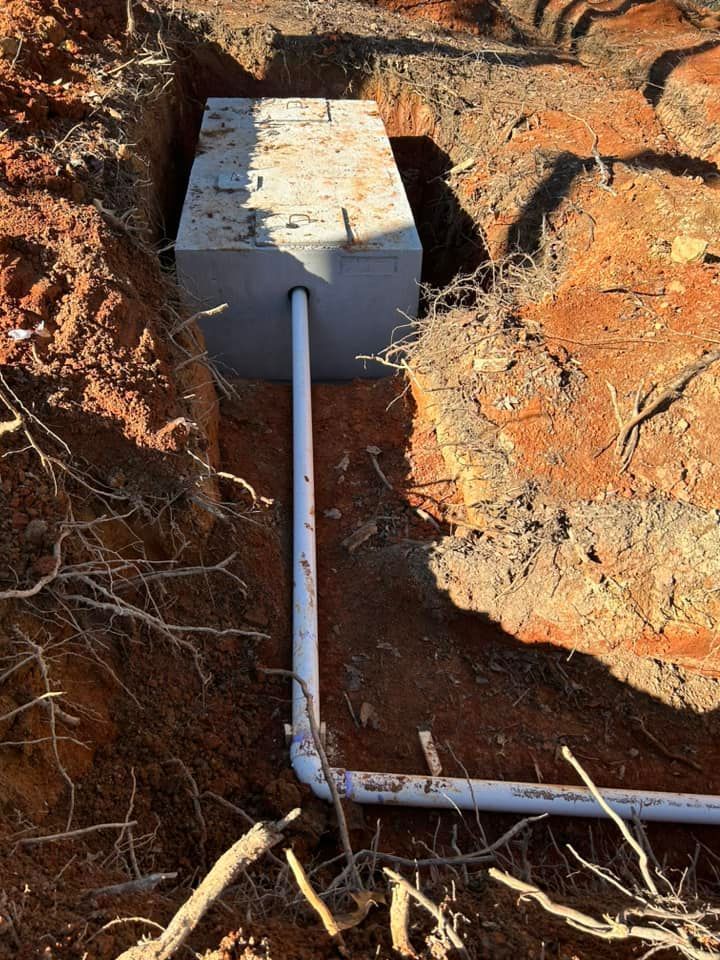 A pipe is connected to a concrete block in the dirt.