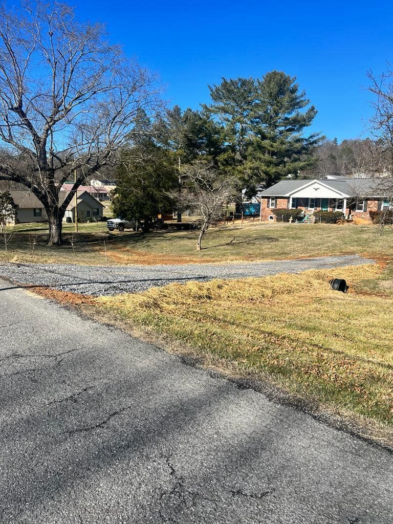 A house is sitting in the middle of a grassy field next to a road.