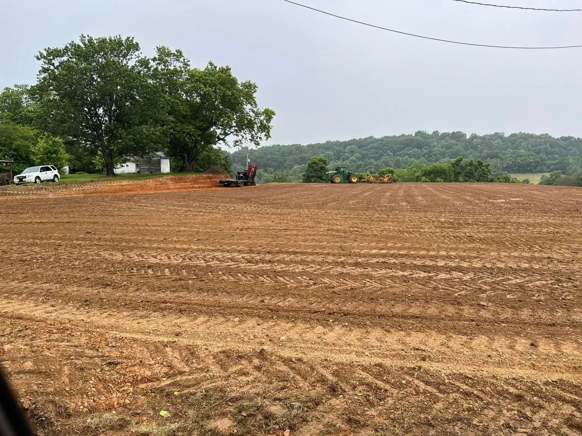 A large dirt field with a tractor in the background.