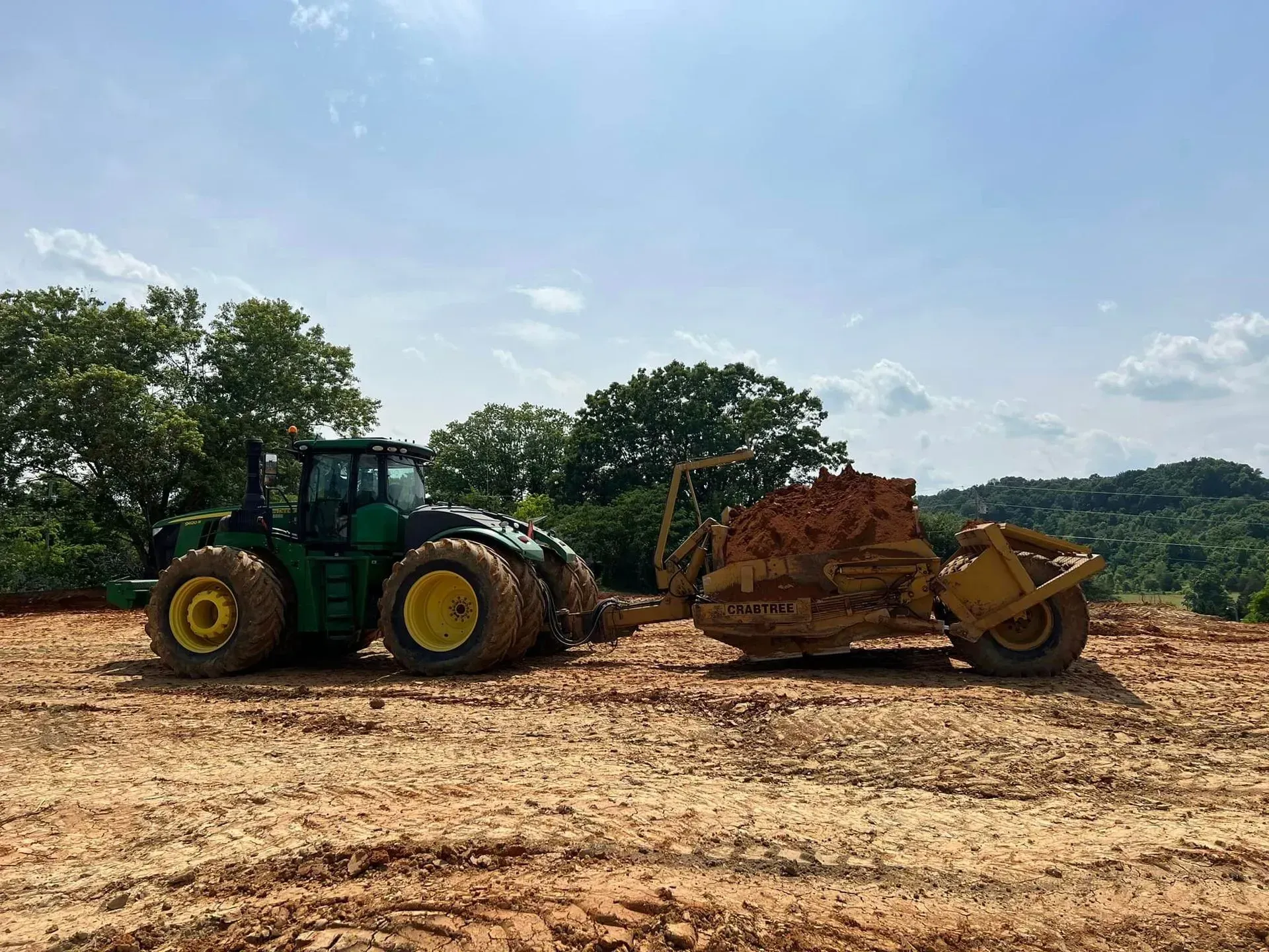 A tractor is pulling a bulldozer through a dirt field.