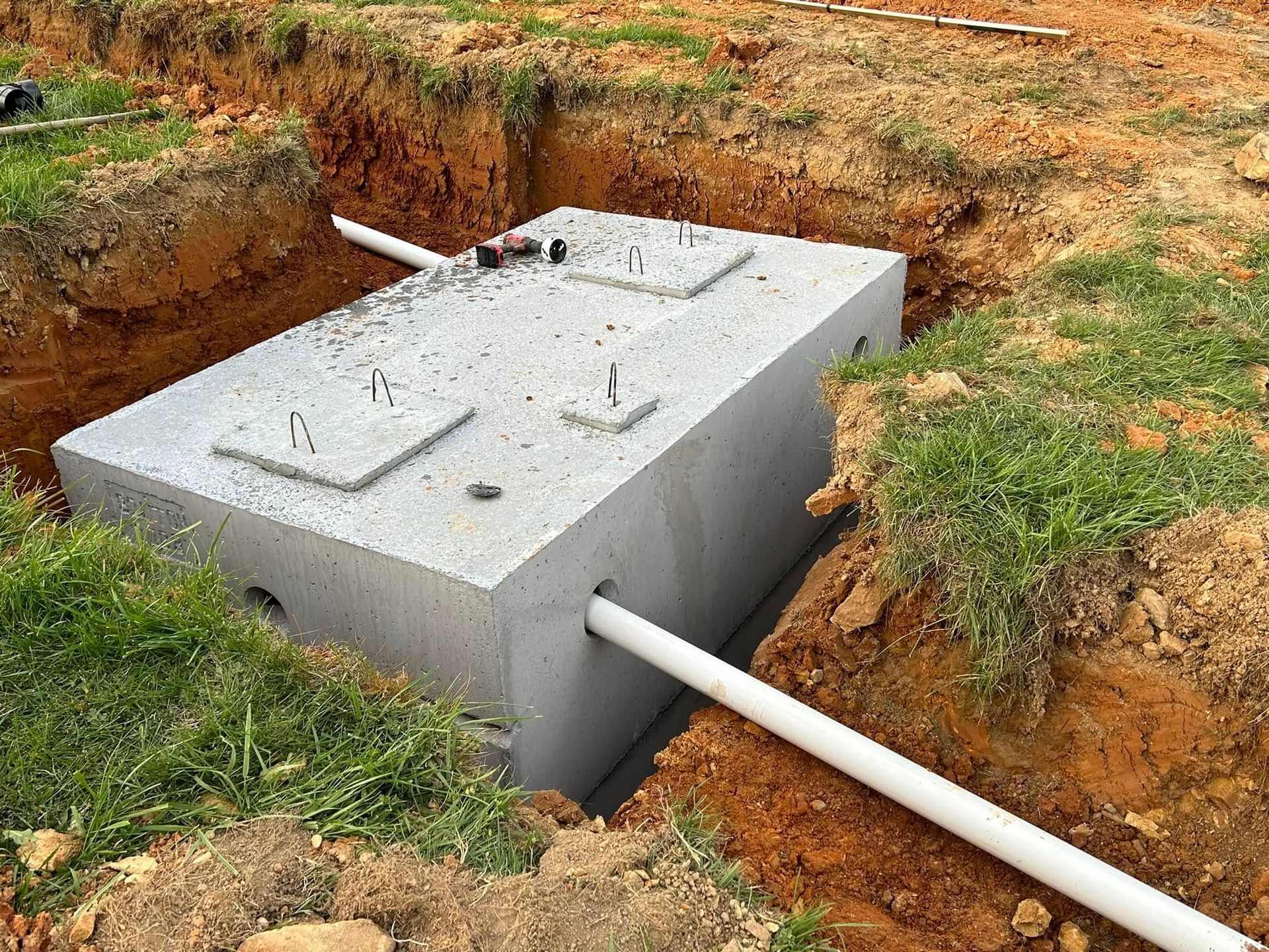 A concrete septic tank is being built in a hole in the ground.