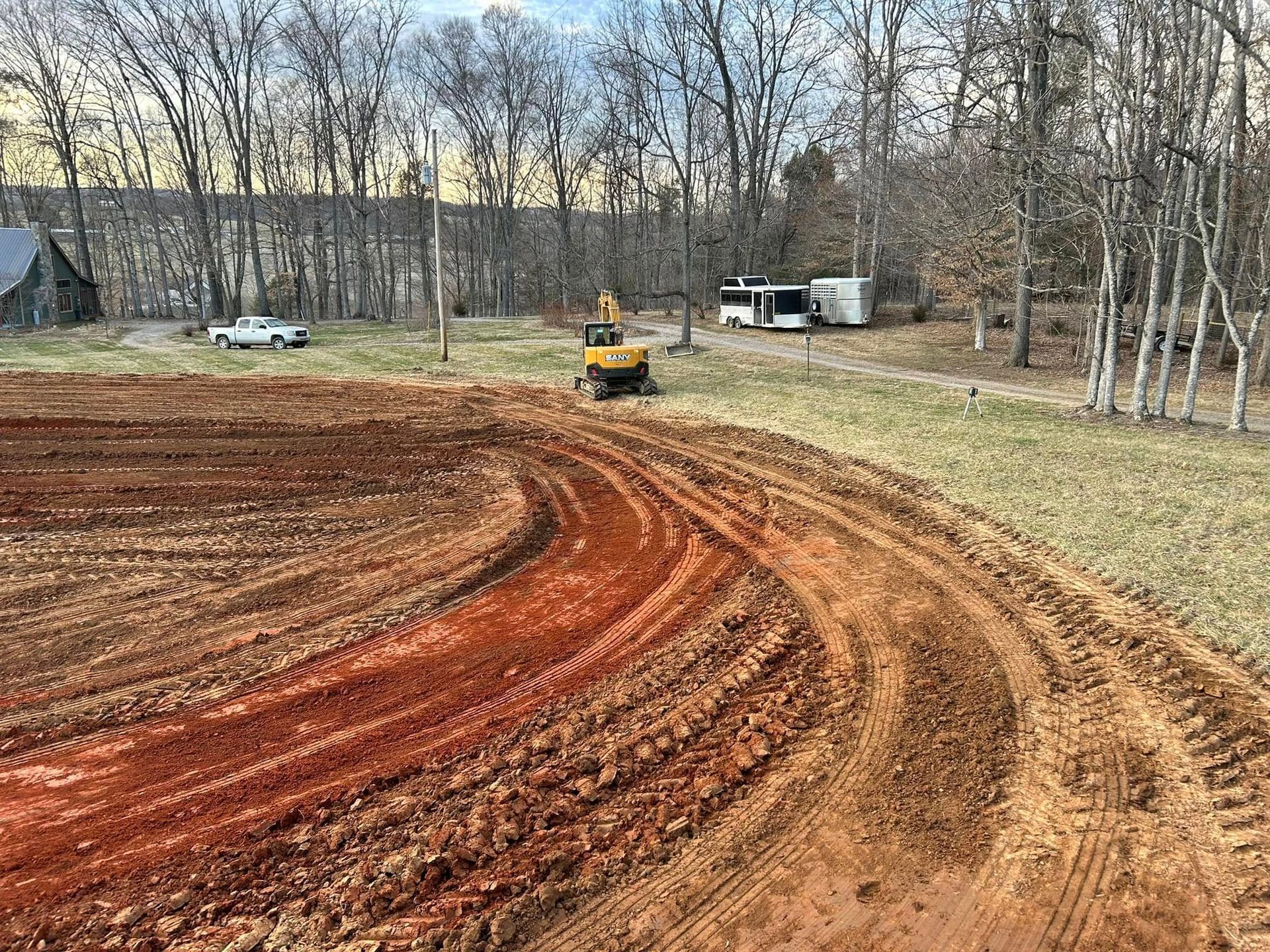 A yellow excavator is driving down a dirt road in a field.