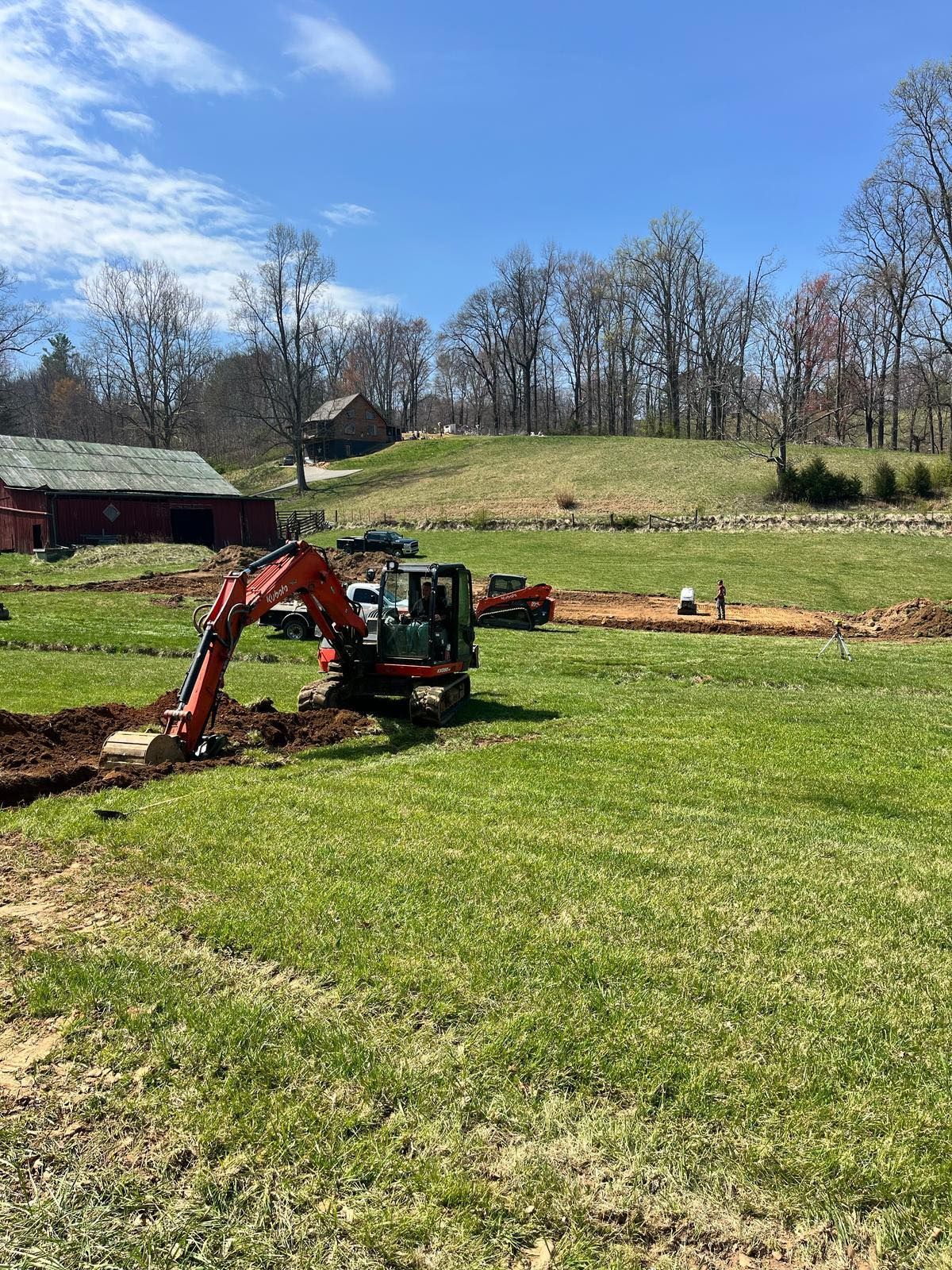 An excavator is digging a hole in a grassy field.