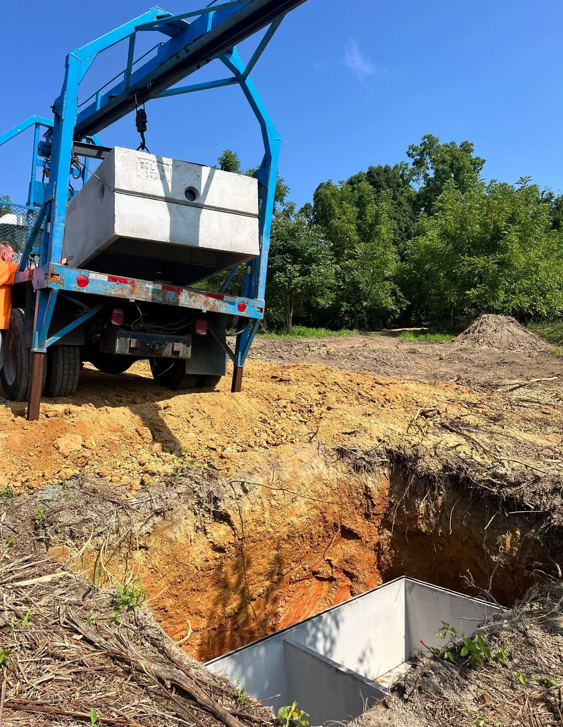 A truck is being lifted into a hole in the ground by a crane.