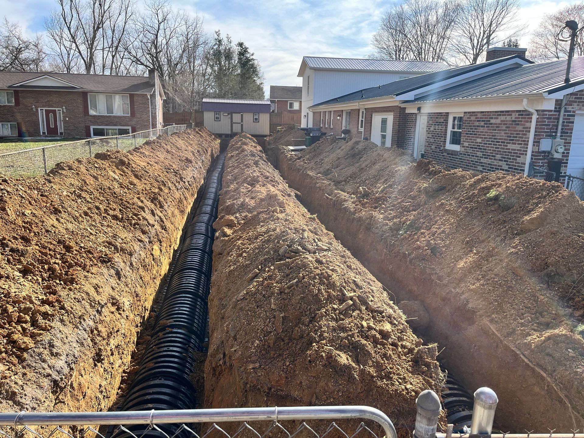 A drain pipe is being installed in the dirt in front of a house.