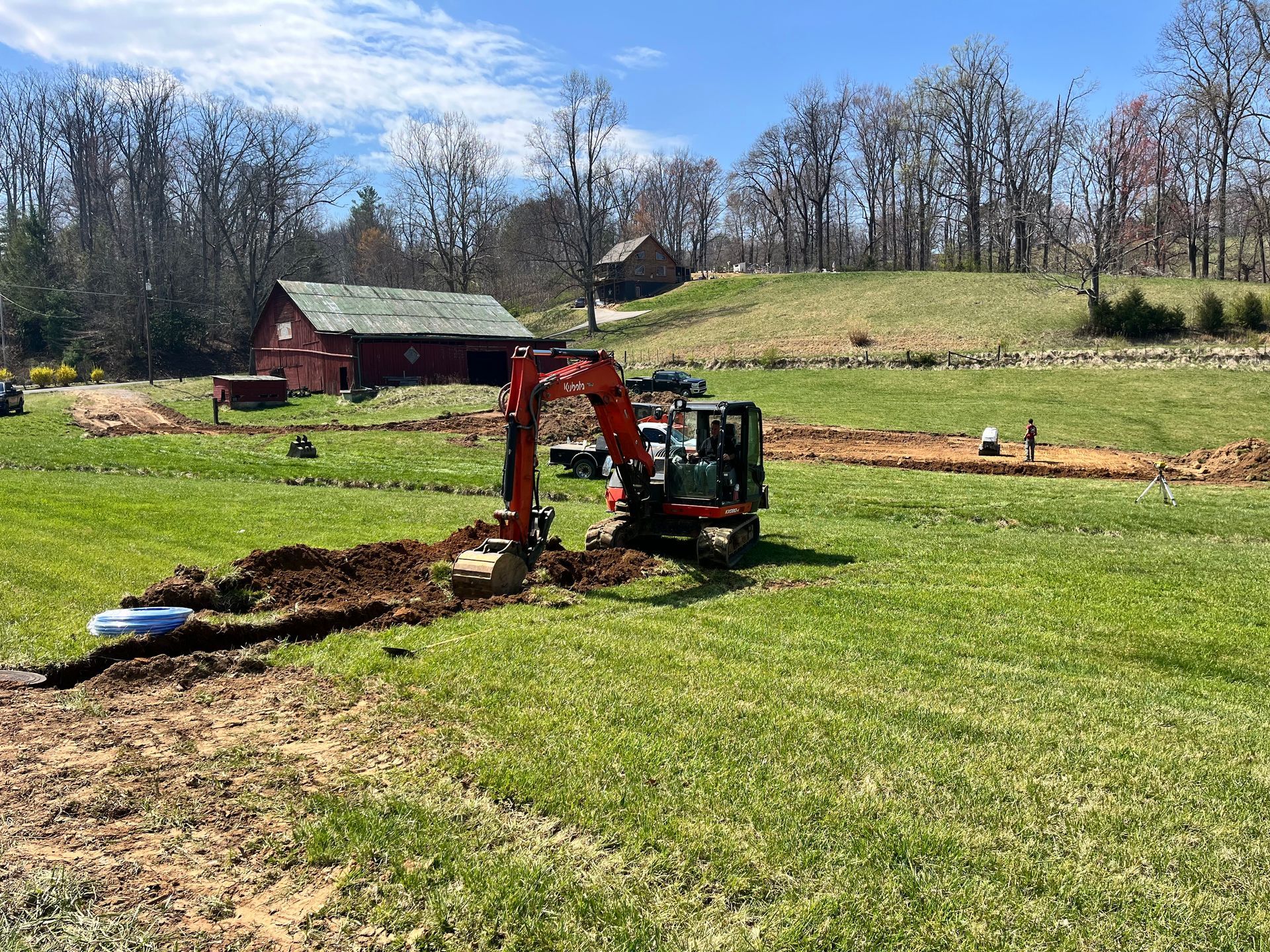 An excavator is digging a hole in a grassy field.