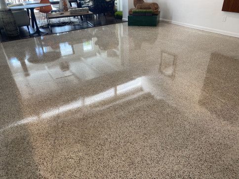 A living room with a shiny concrete floor and a table and chairs.