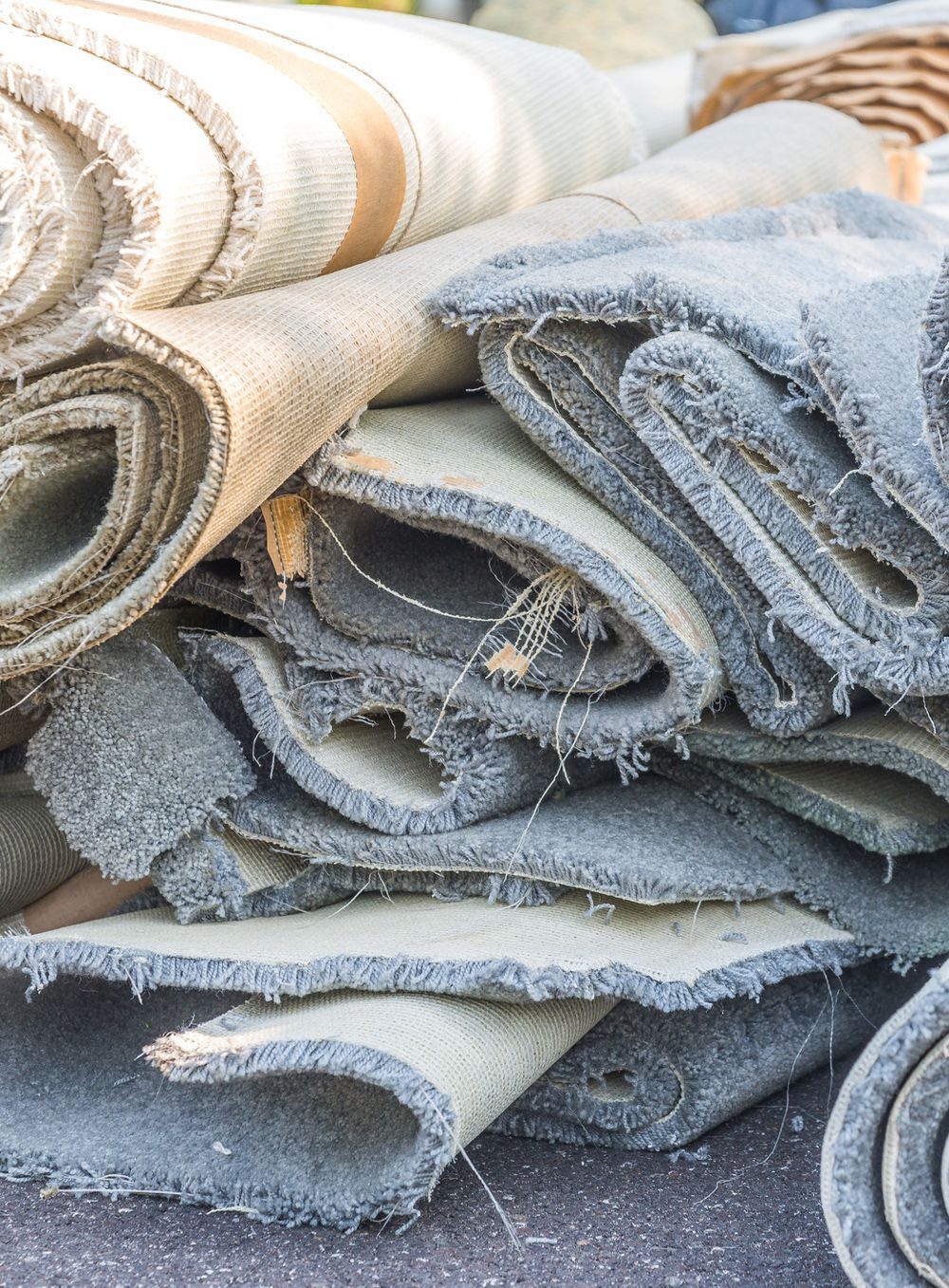 A pile of carpets is stacked on top of each other on the ground.