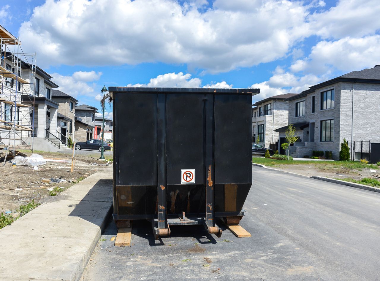 A dumpster is parked on the side of the road in a residential neighborhood.