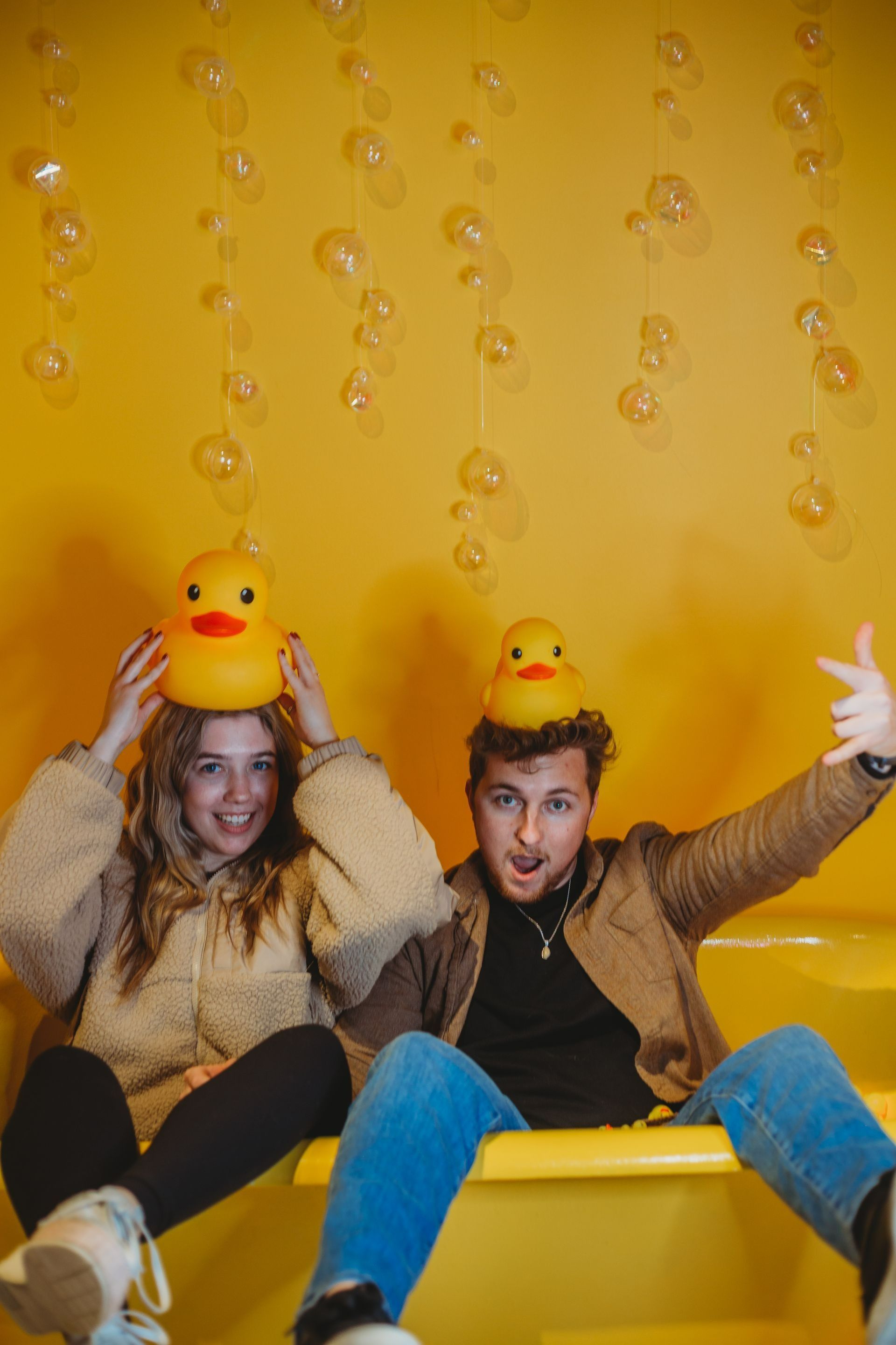 Two people with a rubber duck in head posing for a picture.
