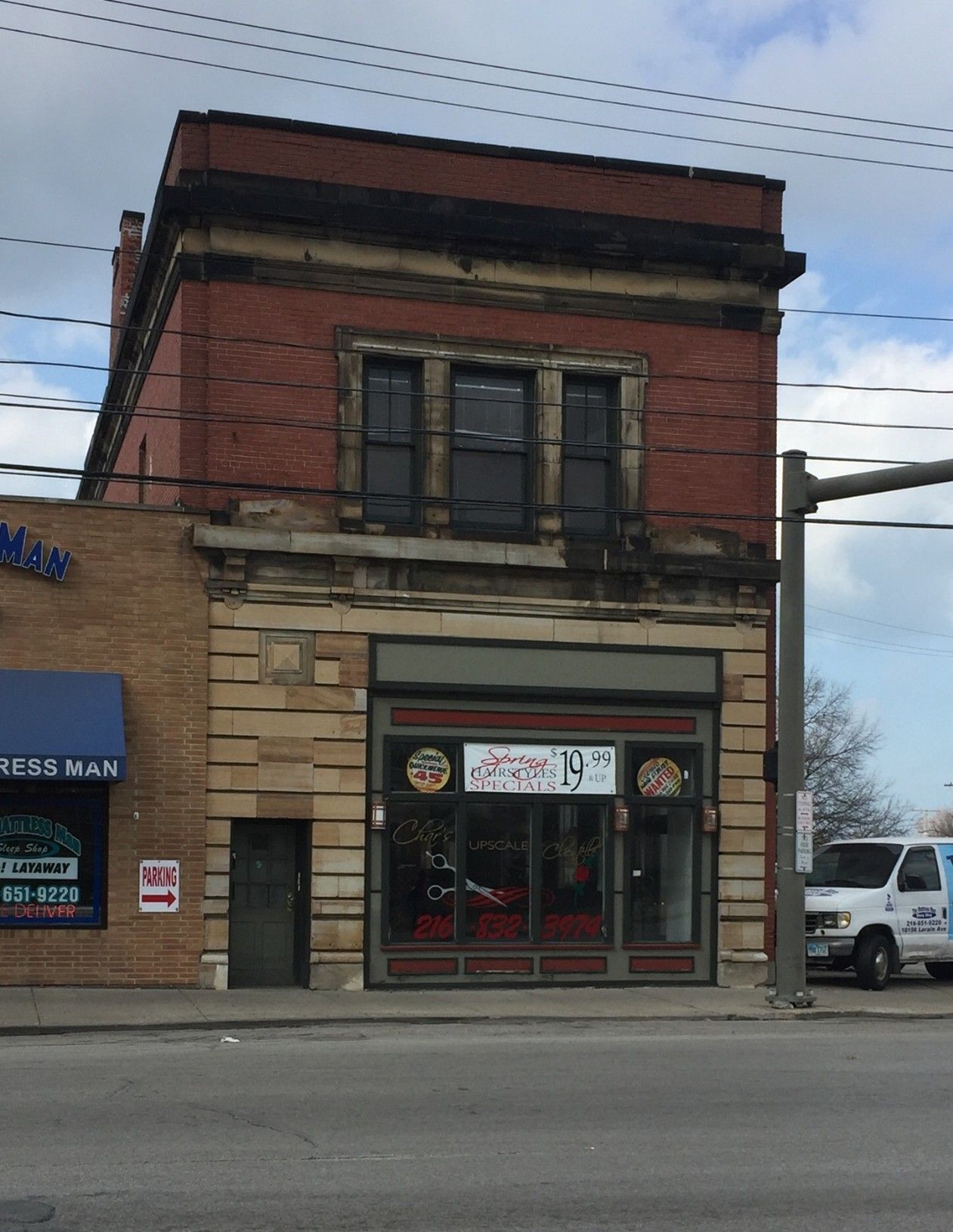 Two-story brick building with tan stone facade; ground floor storefront, second floor windows.