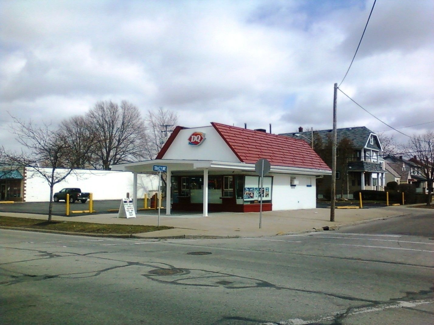 Dairy Queen restaurant on a street corner, red roof, white building, cloudy sky.