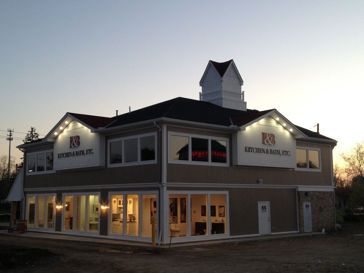 Exterior of a two-story building at dusk, featuring large windows and illuminated signs.