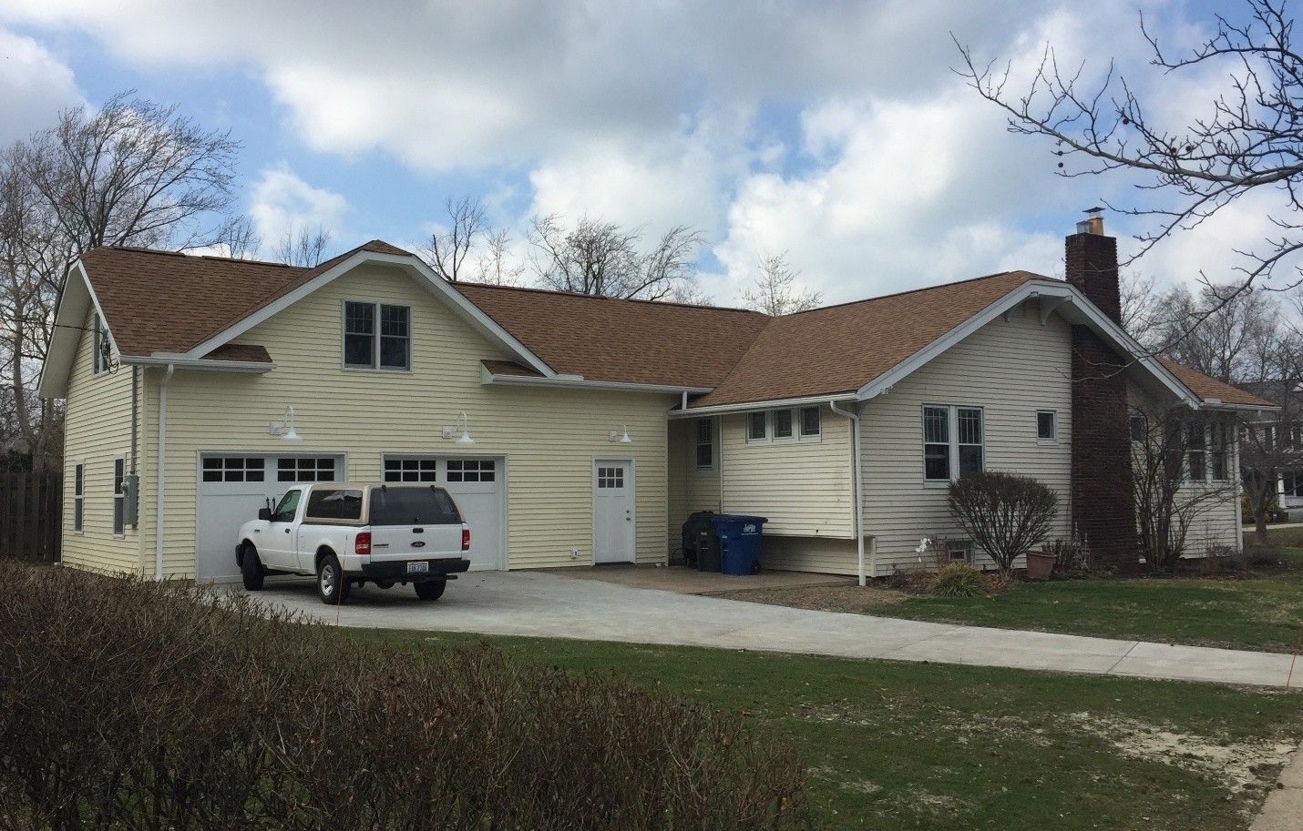 Tan house with attached garage, brown roof, and white pickup truck in the driveway.