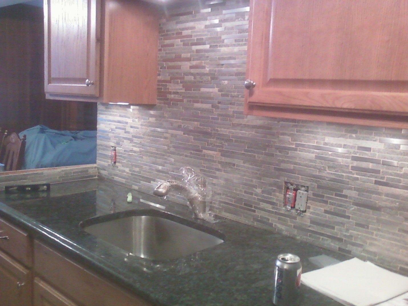 Kitchen countertop with tiled backsplash, cabinets, and sink.