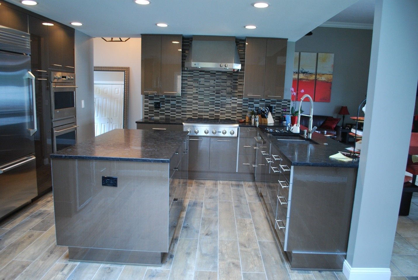 Modern kitchen with dark cabinetry, island, stainless steel appliances, and a tiled backsplash.