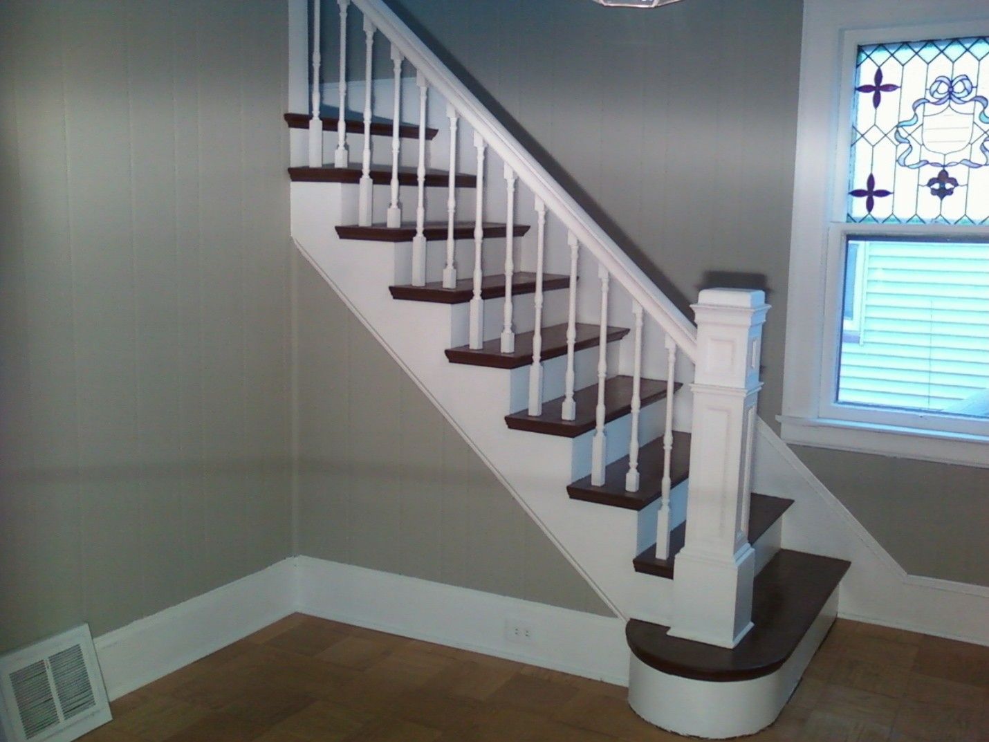 Staircase with white railing, dark brown steps, and stained glass window.