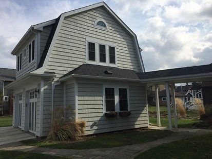 Two-story house with light gray siding, dark roof, and covered carport.