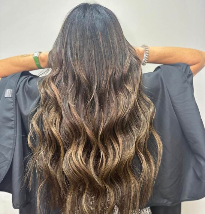 A woman with long hair is holding a black cape over her head.