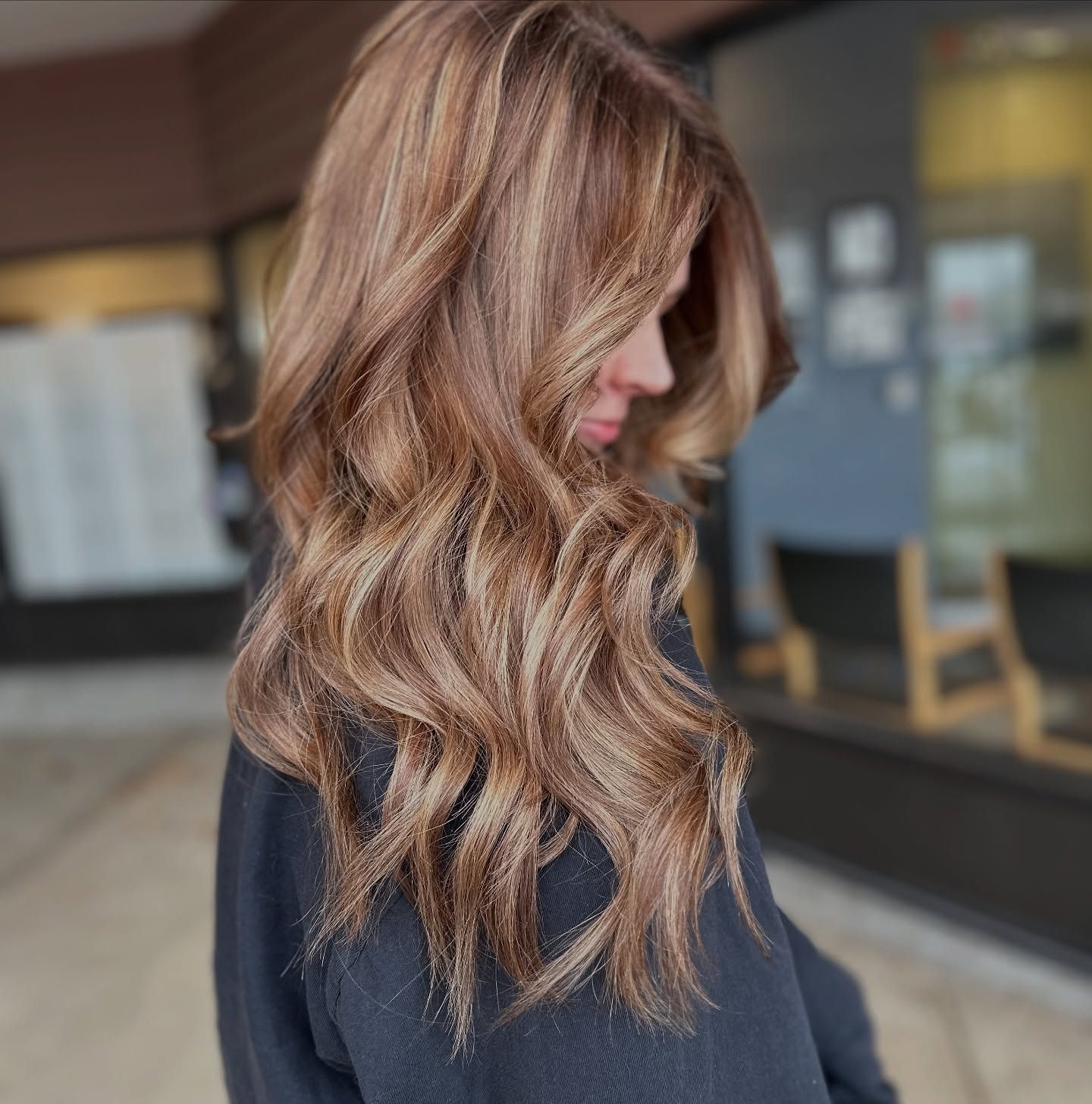 A woman with long brown hair is wearing a black sweater