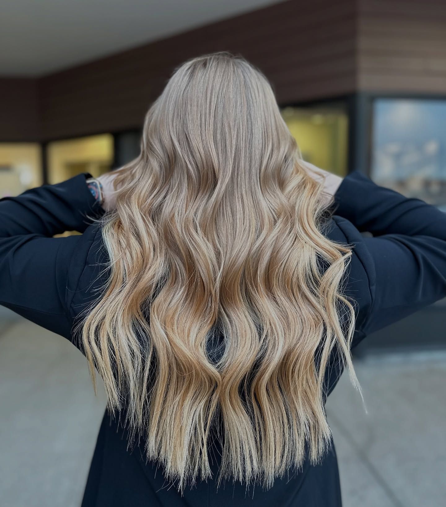 A woman with long blonde hair is wearing a black jacket.