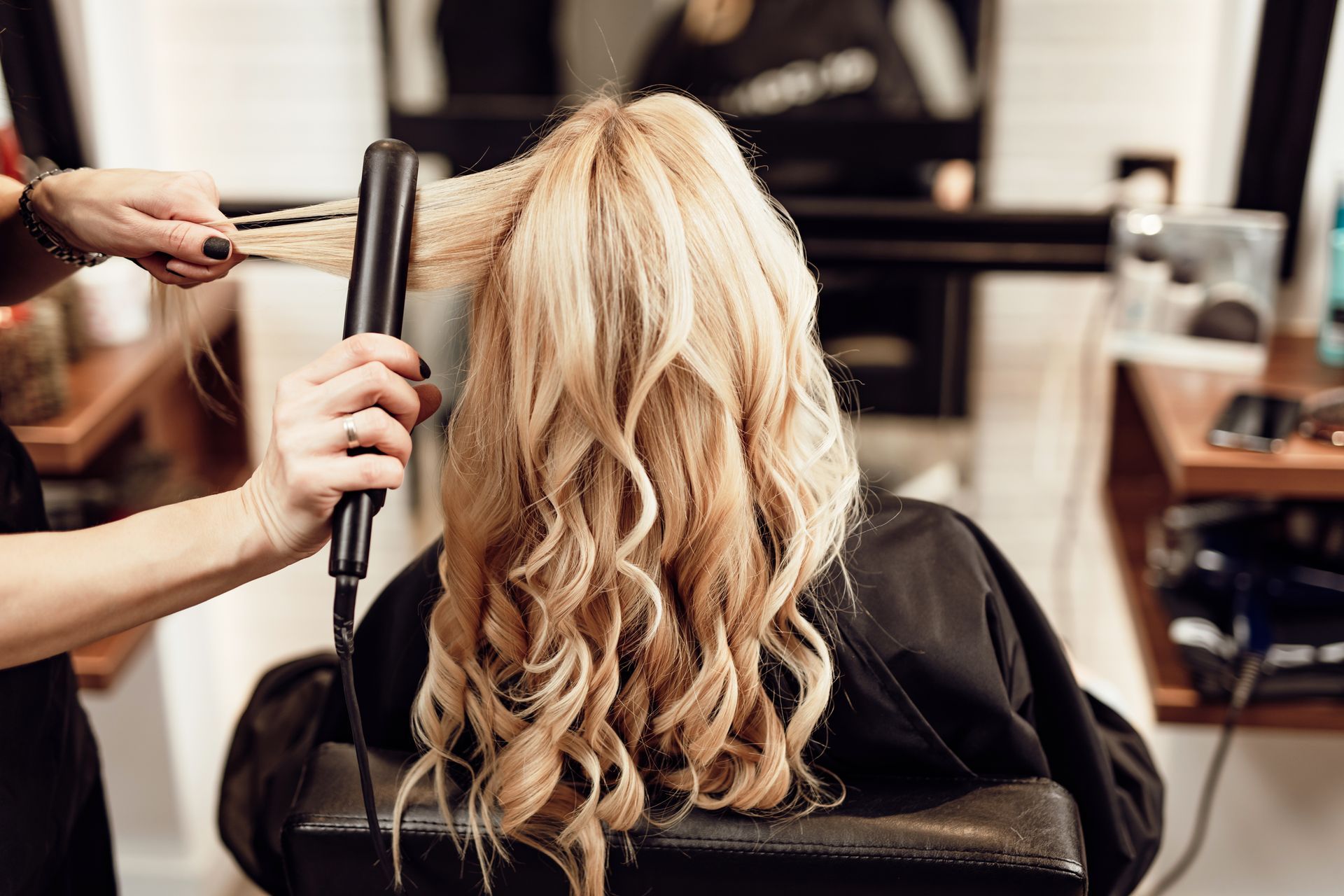 A woman is getting her hair straightened at a salon.