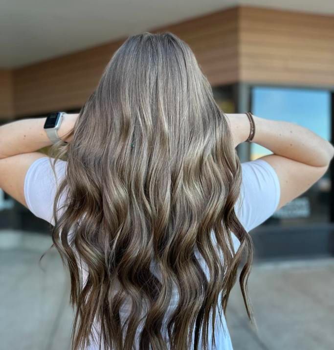 A woman with long wavy hair is wearing a white shirt.