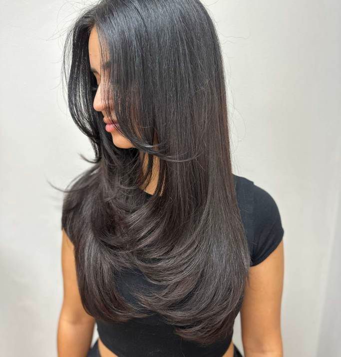 A woman with long black hair is wearing a black crop top.