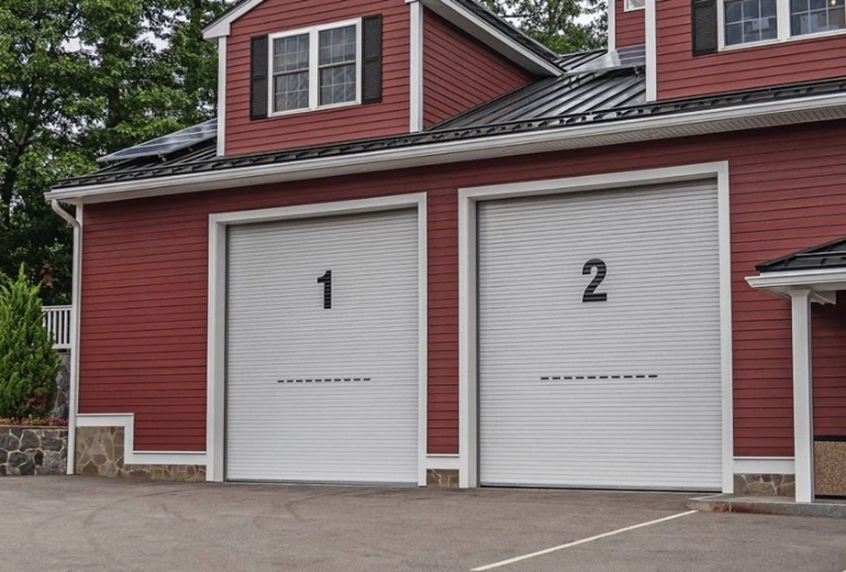 A red house with two garage doors with the numbers 1 and 2 on them.