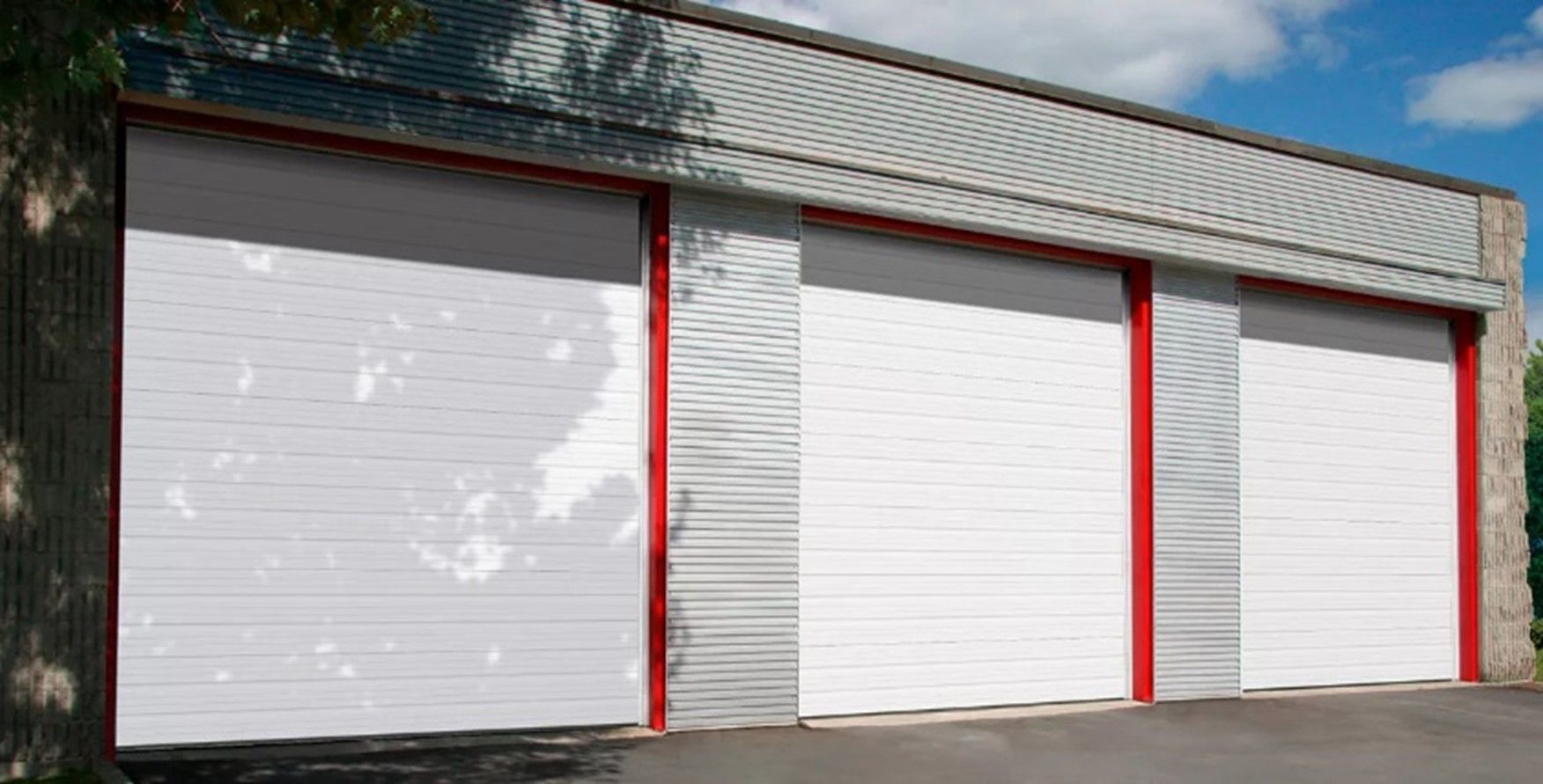 A row of white garage doors with red trim on a building.