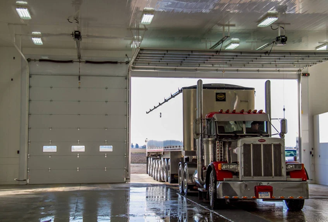 A semi truck is parked in a garage with the door open.