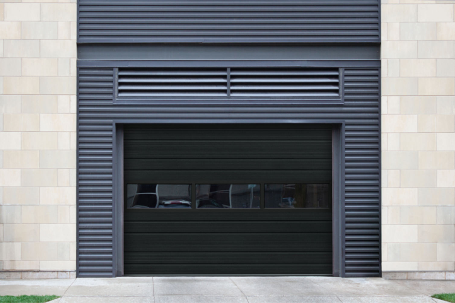A black garage door with a brick wall behind it