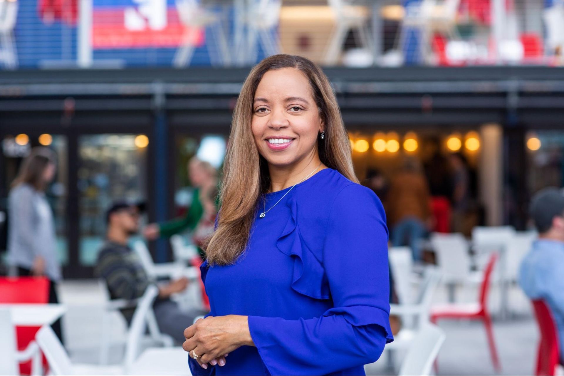 A woman in a blue shirt is standing in front of a crowd of people.