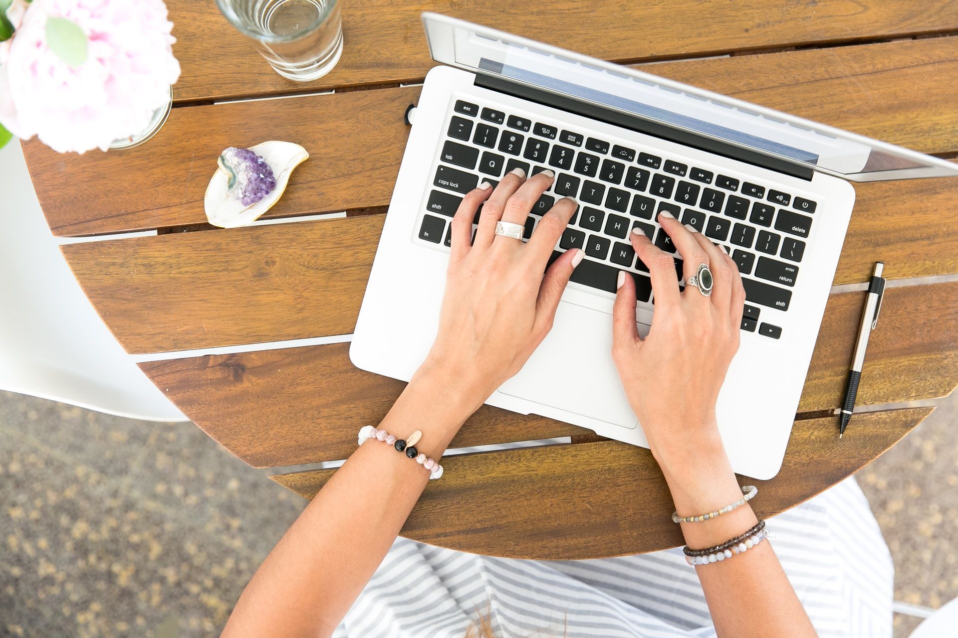 A woman is typing on a laptop computer at a table.