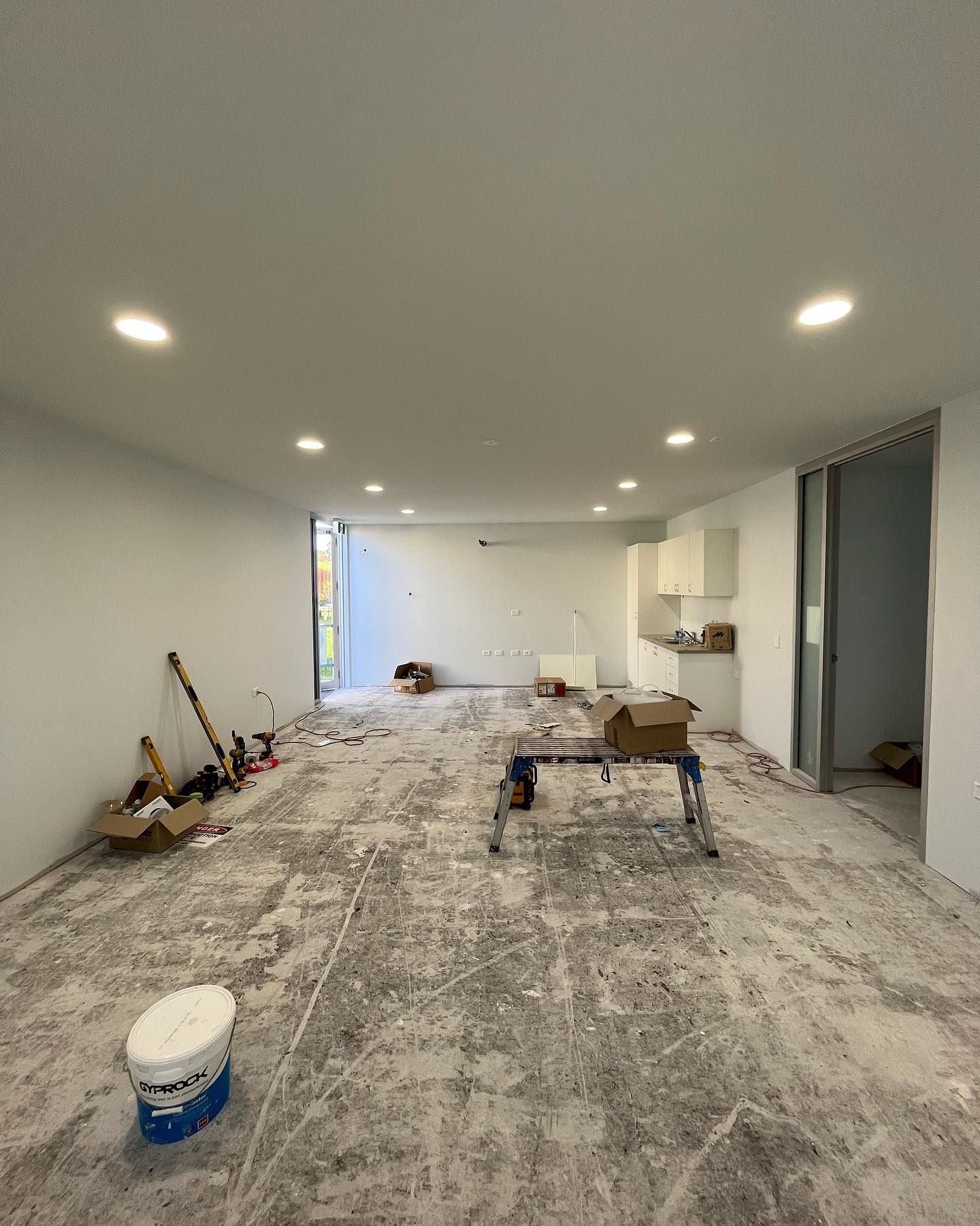 A Empty Room Under Renovation White Walls, Recessed Lighting, and Scattered Debris — Neave Electrical in Forster, NSW