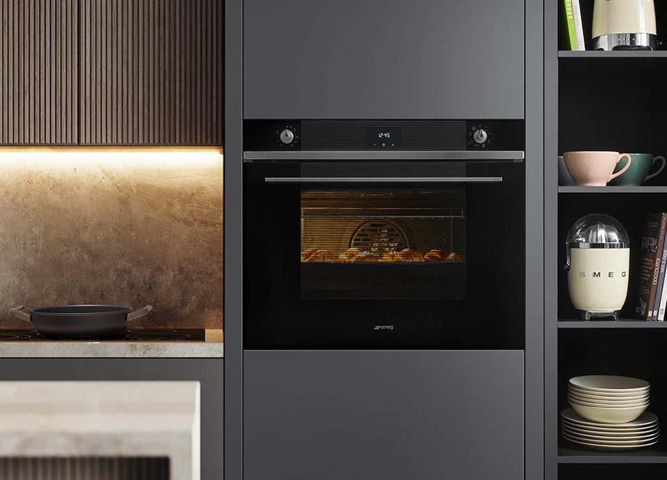 Built-in black oven in a dark gray kitchen; interior view with food cooking.— Neave Electrical in Forster, NSW
