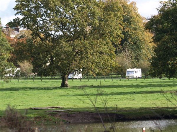 Green field with trees, a small pond, and two white camper trailers.