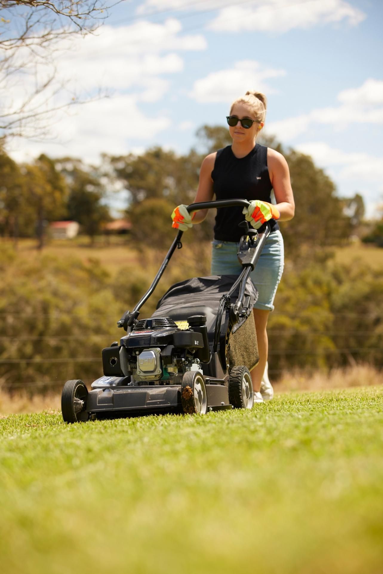 A Woman Is Pushing A Lawn Mower On A Lush Green Field — Cairns Mower City In Parramatta Park, QLD