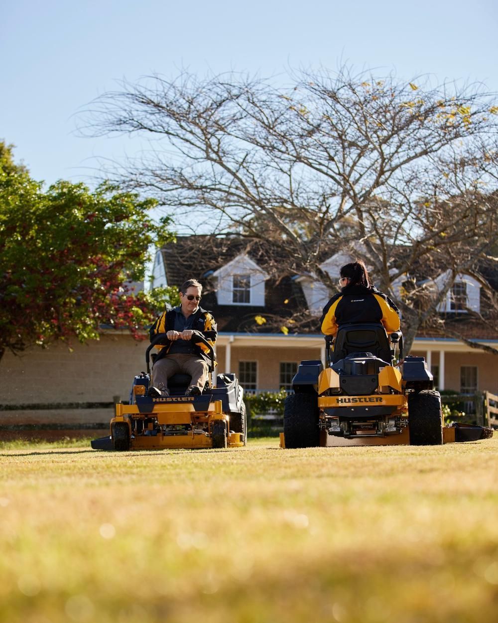 Two Men Are Riding Lawn Mowers On A Lush Green Field — Cairns Mower City In Parramatta Park, QLD