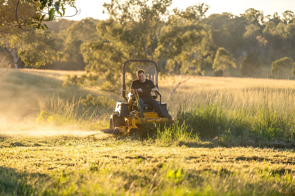 A Man Is Riding A Lawn Mower Through A Grassy Field — Cairns Mower City In Parramatta Park, QLD