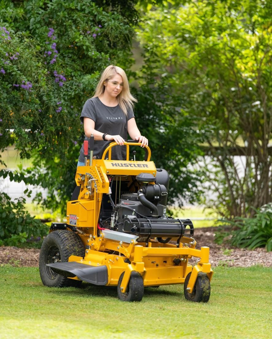A Woman Is Riding A Yellow Lawn Mower On A Lush Green Lawn — Cairns Mower City In Parramatta Park, QLD