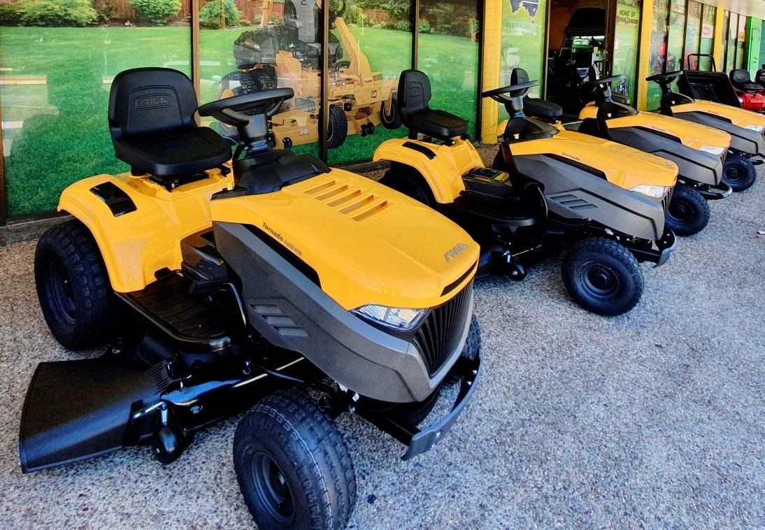 A Row Of Yellow Lawn Mowers Are Parked In Front Of A Building — Cairns Mower City In Parramatta Park, QLD