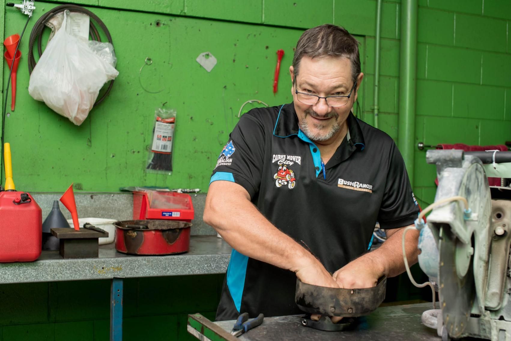 A Man Is Working On A Machine In A Garage — Cairns Mower City In Parramatta Park, QLD