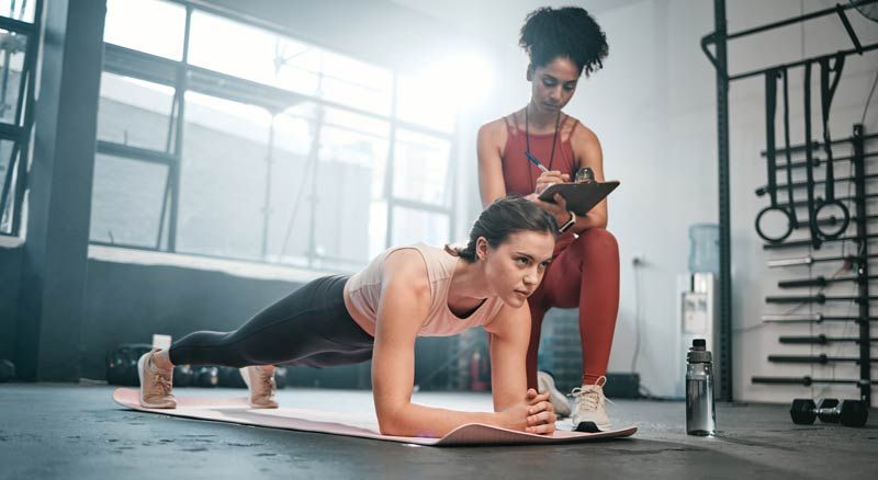 Woman in plank pose at gym representing Why Clients Trust Their Trainer More Than Their Advisor