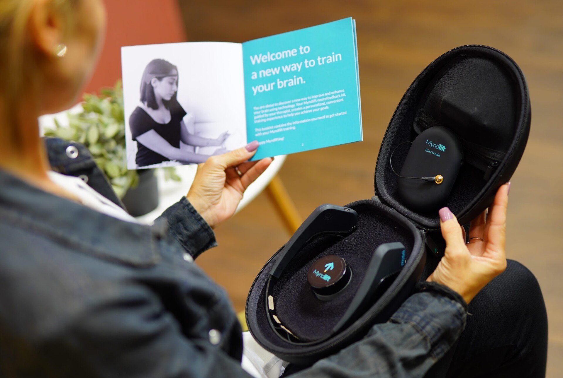 A woman is holding a book and a case with a device in it.